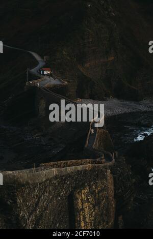 Winding mountain road crossing stone bridge and leading along rocky coastline in Spain at twilight Stock Photo