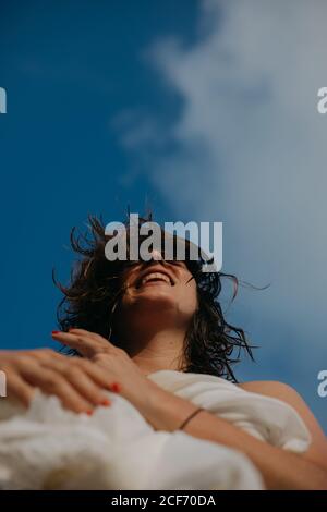 From below of cheerful young Woman with wet hair relaxing on sandy beach on sunny day Stock Photo