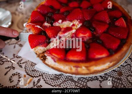 Woman hand cutting strawberry cake with knife Stock Photo