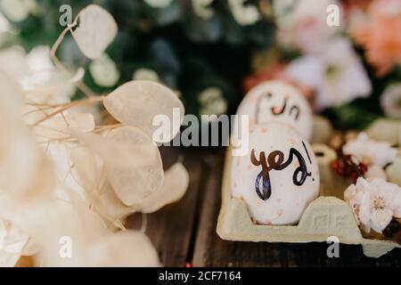Easter eggs hand painted by children with messages in an egg cup on a wooden table Stock Photo