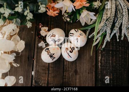 Easter eggs hand painted by children with messages in a wooden table and flowers Stock Photo