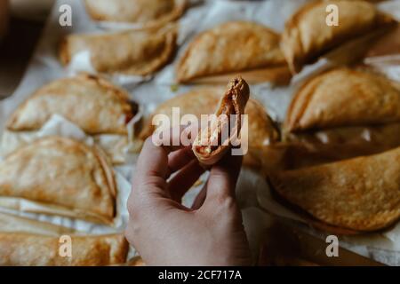 anonymous person eating and Baking tray with composed freshly baked pies patty having golden crispy crust Stock Photo