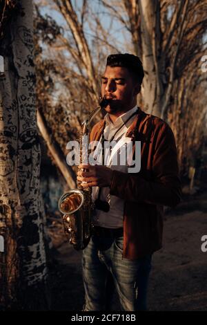 young musician playing the saxophone at sunset Stock Photo