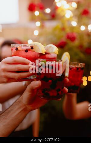 Crop group of friends clinking glasses with colorful berry drinks at summer yard party Stock Photo