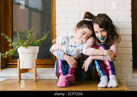 Two smiling sisters sticking out a blue tongue after eating a blue bubble gum Stock Photo