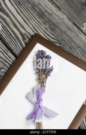 A bouquet of lavender in a photo frame. On brushed pine boards painted black and white. Stock Photo