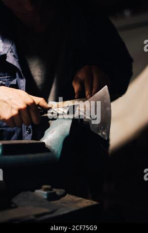 Crop craftsman checking axe in workshop Stock Photo