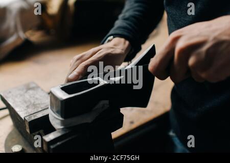 Crop craftsman checking axe in workshop Stock Photo