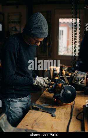 Crop craftsman checking axe in workshop Stock Photo