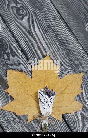 A dried maple leaf and a lavender bouquet on brushed black and white pine boards. Stock Photo