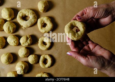 Top view of anonymous Woman making rings from soft dough while preparing doughnuts over table in kitchen Stock Photo