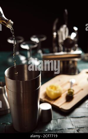 From above process of pouring alcohol drink from bottle into shaker with ice cubes during cocktail preparation at counter Stock Photo
