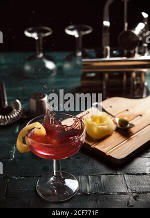 From above of red alcohol cocktail with splashes served in coupe glass garnished with lemon on bar counter Stock Photo