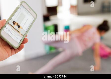 Smartphone with example of yoga pose on screen and Woman practicing this pose in studio Stock Photo