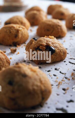 Fresh homemade brown cookies with chocolate on white table against blurred white wall Stock Photo