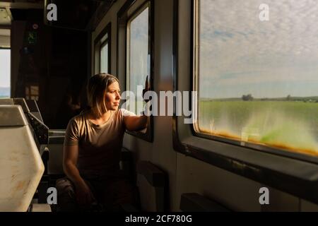 Female soldier looking out window while travelling through countryside in military vehicle Stock Photo