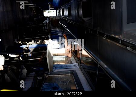 Side view of strong female soldier pointing up while looking at sky through ceiling window of military base Stock Photo