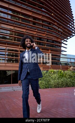 Ethnic smiling businessman talking on smartphone Stock Photo