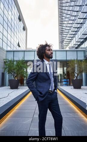 Confident ethnic businessman standing on downtown street Stock Photo