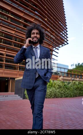 Ethnic smiling businessman talking on smartphone Stock Photo