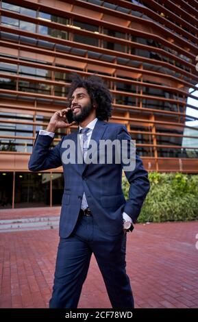 Ethnic smiling businessman talking on smartphone Stock Photo