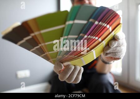 Builder in gloves shows color samples for repair Stock Photo