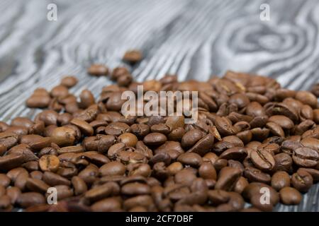 Coffee beans on a black-and-white brushed pine plank surface. Close-up shot. Stock Photo