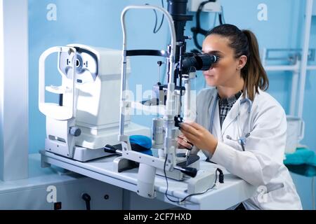 Young medical worker looking and using microscope at workplace on blurred background Stock Photo