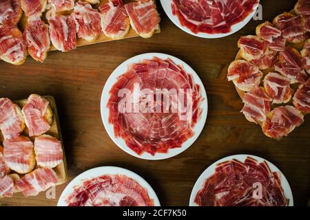 From above fresh red juicy sliced meat on white round plate and wooden stand on table Stock Photo