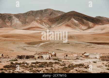 Dilapidated old buildings in mountain desert under cloudy sky Stock Photo