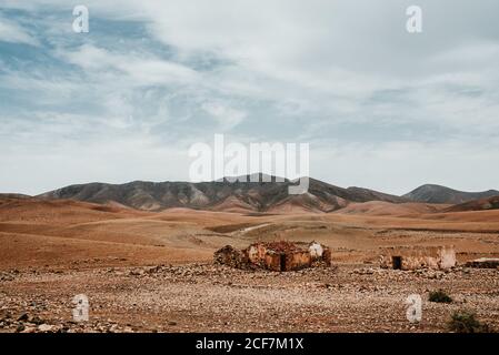Dilapidated old buildings in mountain desert under cloudy sky Stock Photo