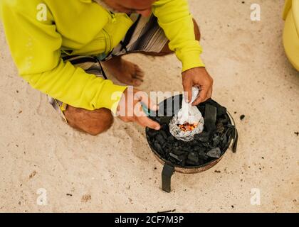 Tanned man cooking on camping stove beside parked mini van Stock Photo