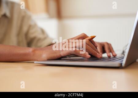 Close-up of man sitting at the table and typing on laptop computer he working online Stock Photo