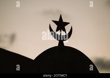 Silhouette of Muslim star and crescent sign on top of dome against blurred background in Gambia Stock Photo