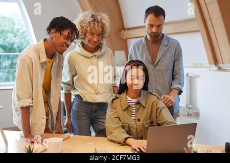 Group of business team looking at presentation on laptop which his colleague showing to them they working in team Stock Photo
