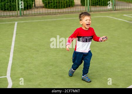 POZNAN, POLAND - Aug 26, 2020: Small crying boy walking on a green sport field Stock Photo