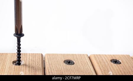 The screwdriver twists the self-cut into wooden boards. Construction tools, home repairs. Stock Photo