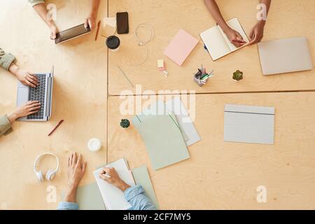 Close-up of group of business people sitting at the table working on computers and making notes in notepad they planning work together Stock Photo