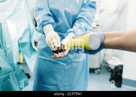 Crop hands of medic pouring iodine to tampon for disinfecting patient during surgery in operating room Stock Photo
