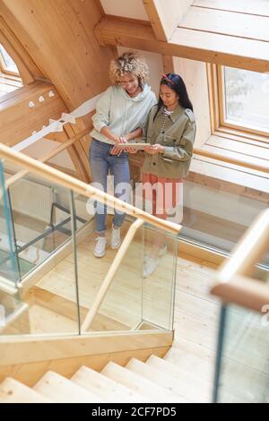 Two colleagues using digital tablet together while standing on wooden staircase Stock Photo