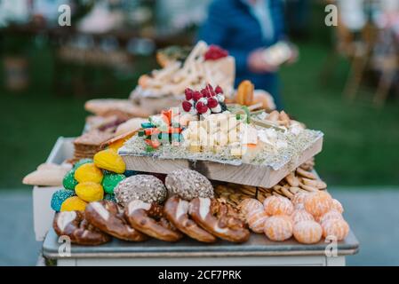 Wooden tray with canapes placed on tray with cookies and fruits in candy bar served during wedding ceremony outdoors Stock Photo