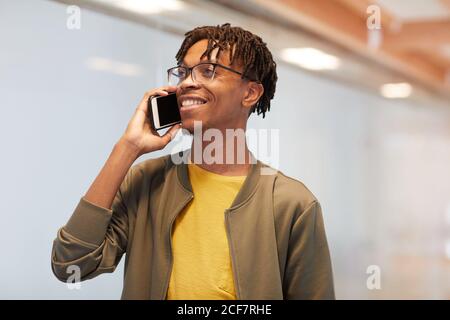 African young man talking on mobile phone and smiling while standing at office Stock Photo