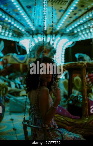 Beautiful Woman enjoying ride on carousel on funfair during summer evening on blurred background Stock Photo