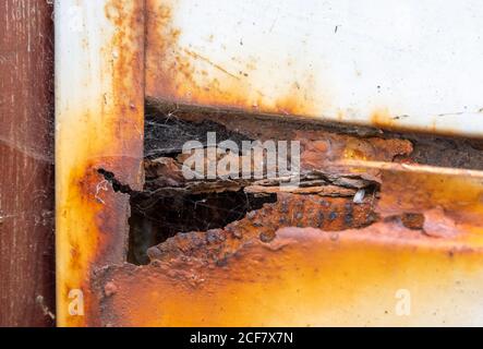 Rusty garage door. Damaged rusting metallic garage door covered in rust (AKA Iron oxide, Iron(III) oxide, Ferric oxide). Stock Photo