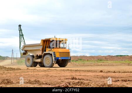 Big yellow mining truck working in the limestone open-pit. Loading and transportation of minerals in the dolomite mining quarry. Belarus, Vitebsk, in Stock Photo