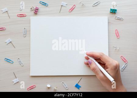 School office supplies on wooden background. Back to school concept. White board with hands for copy space. Top view ready for your design Stock Photo