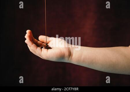 Appetizing melted hot chocolate being poured on cropped unrecognizable person hand placed on dark background Stock Photo