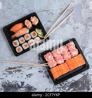 Sushi delivery box with maki, gunkan, nigiri sushi and wooden sticks. Food delivery concept background Stock Photo