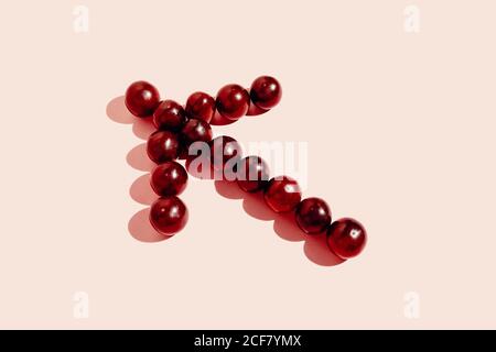 Top view of red grapes arranged in arrow showing direction on pink background Stock Photo