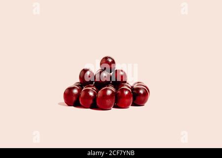Pile of fresh red grapes arranged on pink surface in studio Stock Photo
